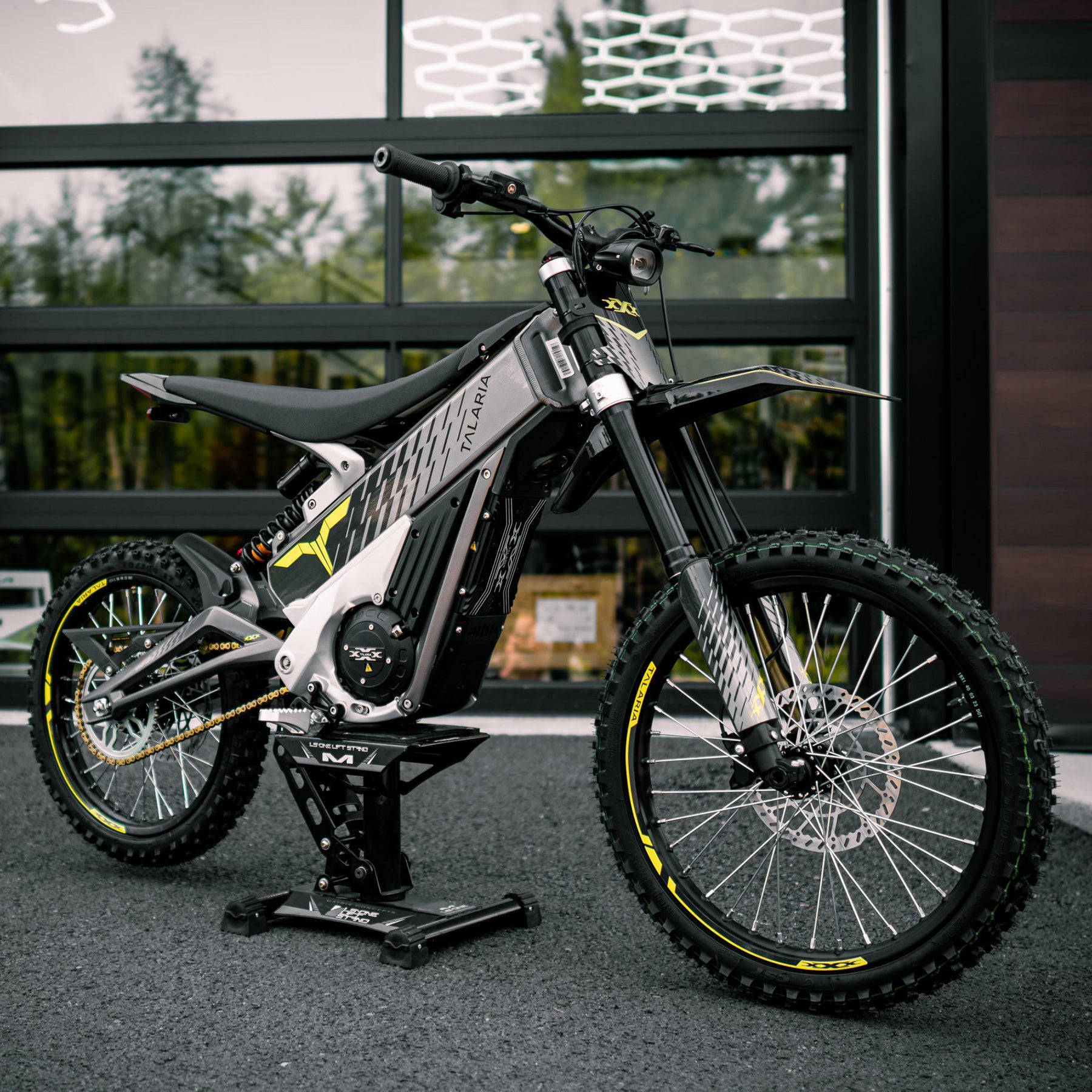 Talaria XXX electric motorcycle 1907mm x 805mm x 1102mm, off-road design, on a bike stand near a garage