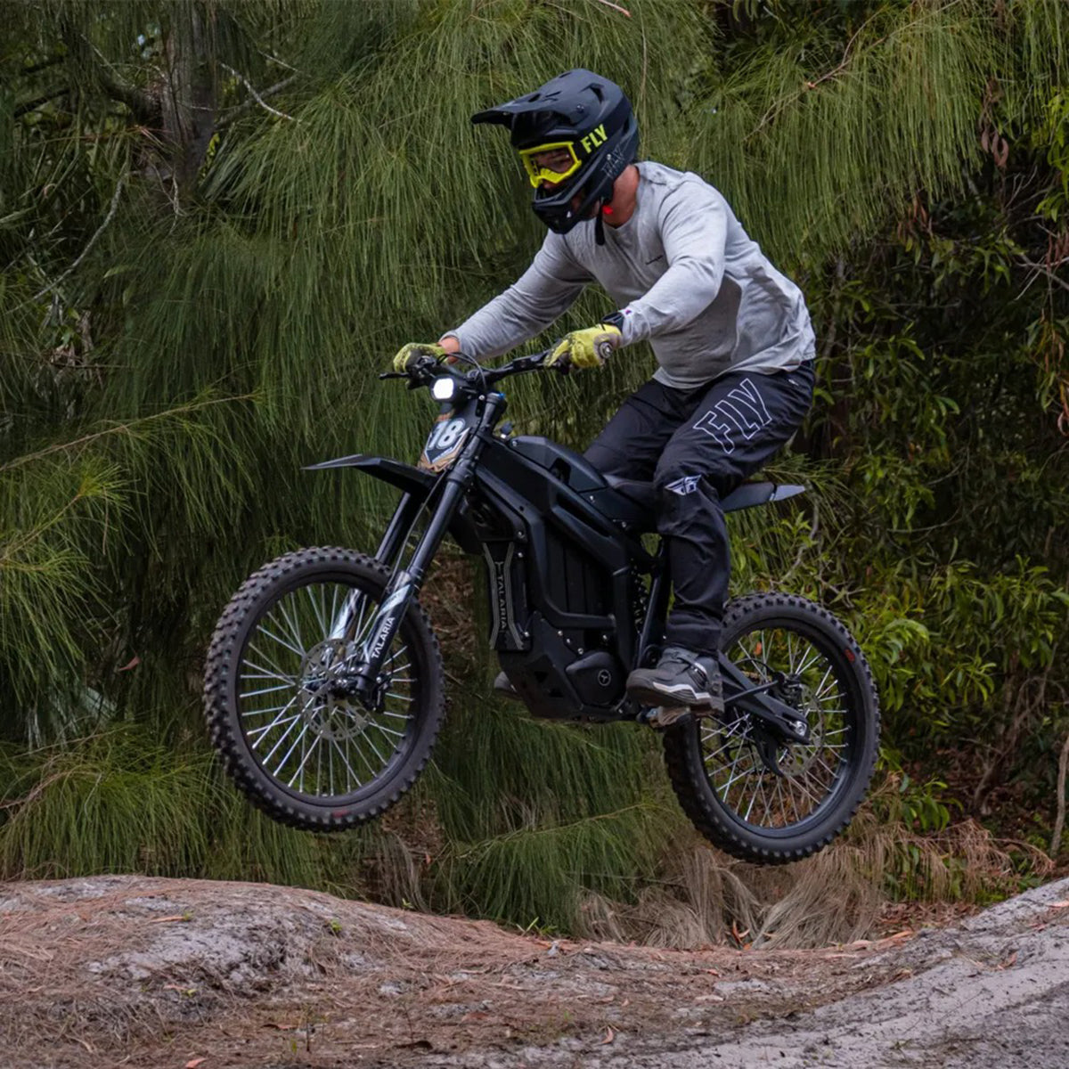 Rider on Talaria Sting R MX4 jumping over a trail, showcasing its 60V battery, IPM motor, and 19-inch off-road tires